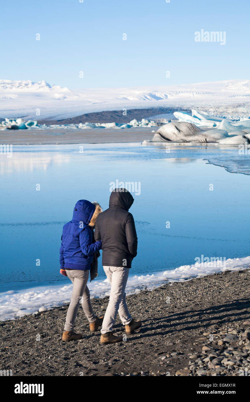Couple touristes se promenant bras dans le lagon Glaciaire de Jokulsarlon, au bord du parc national de Vatnajokull, Islande en février Banque D'Images