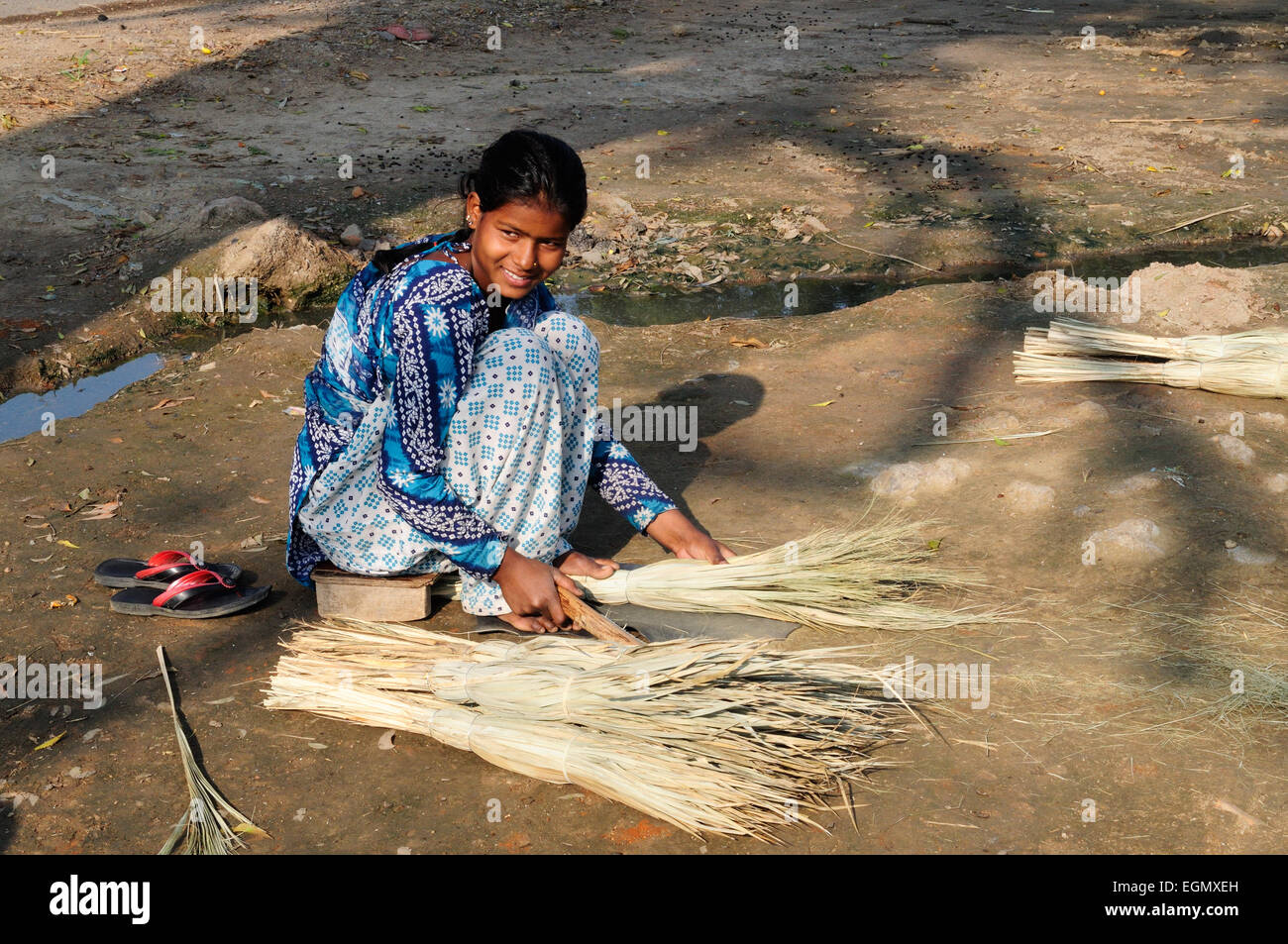 Femme indienne assise sur le sol en herbe traditionnelles brosses reed Rajasthan Inde Banque D'Images
