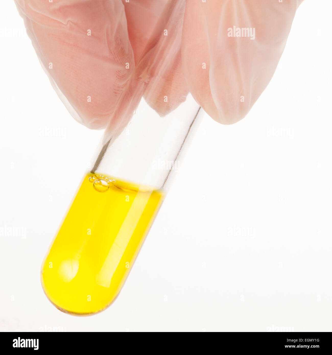 Doigts holding test tube de liquide jaune. Banque D'Images