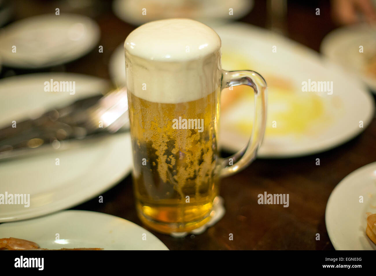 Verre à bière moussante sur table big head Banque D'Images