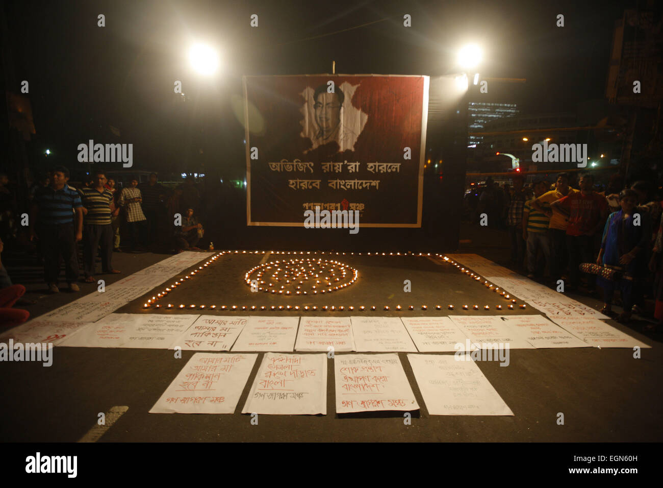 Dhaka, Bangladesh. Feb 27, 2015. Un militant du Bangladesh bougie allumée devant une affiche présentant un portrait de Avijit Roy comme d'autres se réunissent au cours d'une manifestation contre le Roy de Dhaka, Bangladesh, le vendredi 27 février, 2015. Armé d'un couteau une foule a frappé à mort un blogger bangladais dont les écrits sur la religion a apporté des islamistes radicaux des menaces. Avijit Roy, d'athée qui prône la laïcité, a été attaqué à Paris alors qu'il marchait d'une foire du livre avec sa femme, qui a été blessé dans l'attaque. Personne n'a été arrêté mais les policiers disent qu'ils étudient un groupe islamiste local que prai Banque D'Images