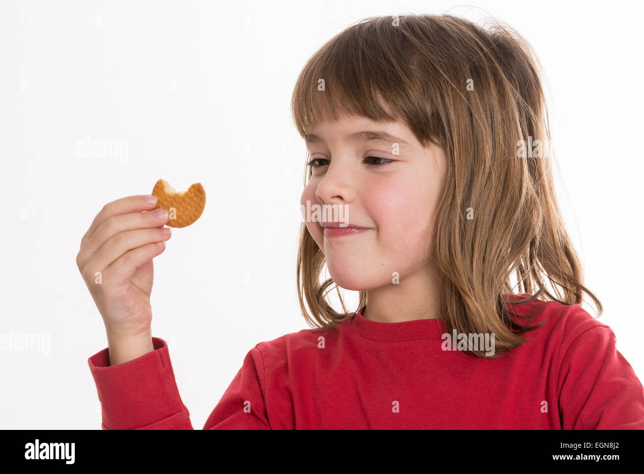 Little girl eating a cookie isolé sur fond blanc Banque D'Images