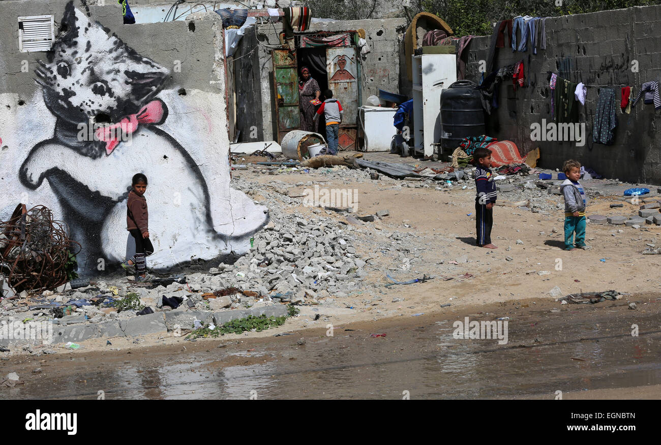 Gaza, l'offensive israélienne sur la bande de Gaza en juillet et août derniers. Feb 27, 2015. Les enfants palestiniens jouer à côté d'une peinture murale d'un chaton, qui a été peint par l'artiste de rue britannique Banksy, sur les vestiges d'une maison qui a été détruit pendant les 50 jours de l'offensive israélienne sur la bande de Gaza en juillet et août derniers, dans le nord de la bande de Gaza ville de Beit Hanun le 27 février 2015. © Yasser Qudih/Xinhua/Alamy Live News Banque D'Images