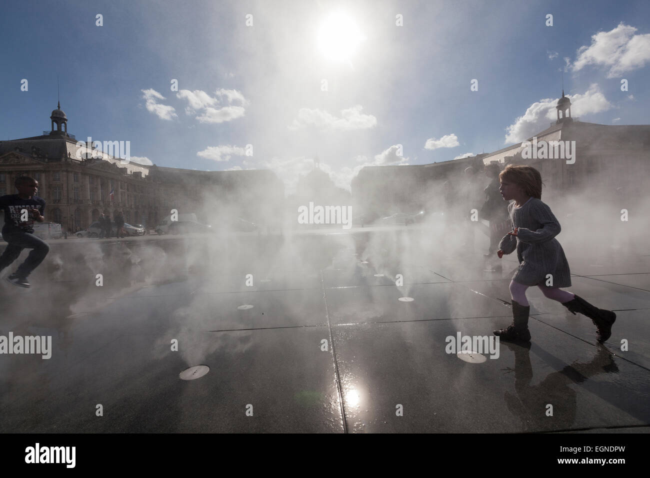 Enfants jouant dans le bain à vapeur en miroir d'eau en place de la Bourse. Banque D'Images