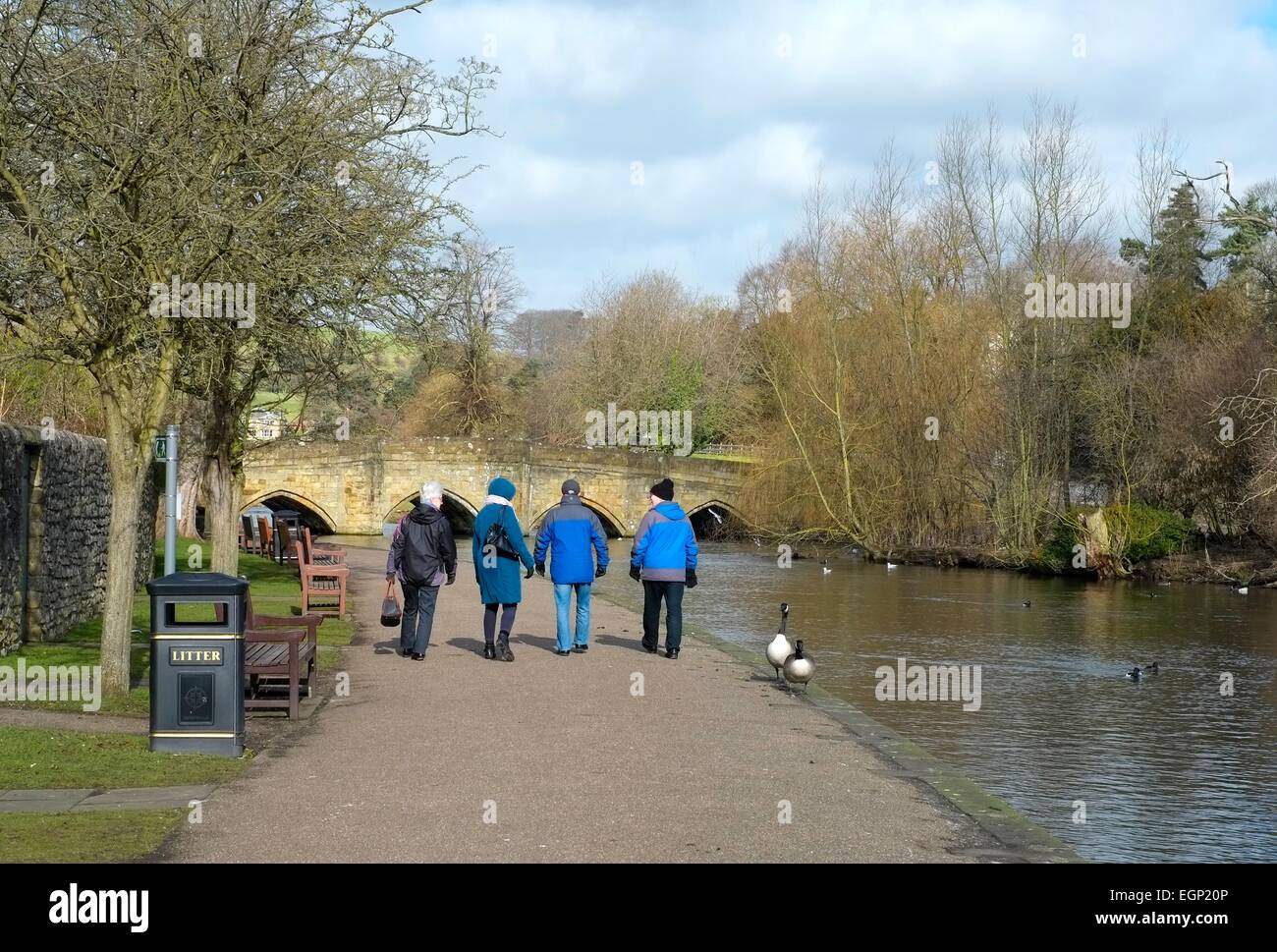 Personnes âgées Personnes âgées de marcher le long de la rivière Wye de bakewell avec le pont du 13ème siècle dans l'arrière-plan le Derbyshire, Angleterre Banque D'Images