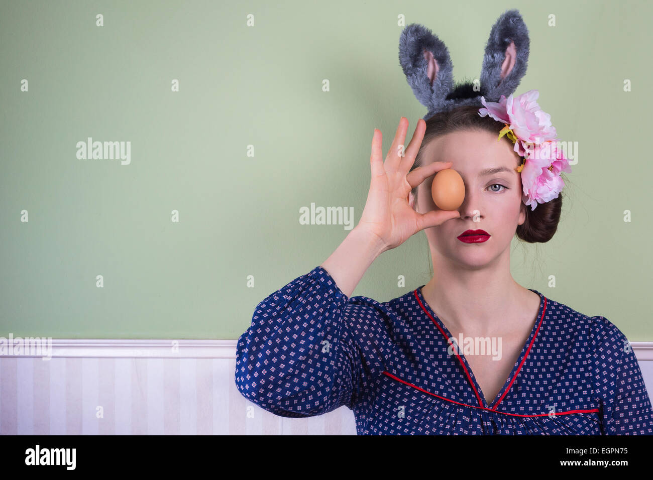Portrait d'une dame avec oreilles de lapin tenant un oeuf devant son visage Banque D'Images