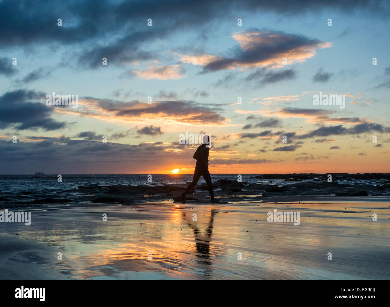 L'homme en marche, jogging sur la plage au lever du soleil. UK Banque D'Images