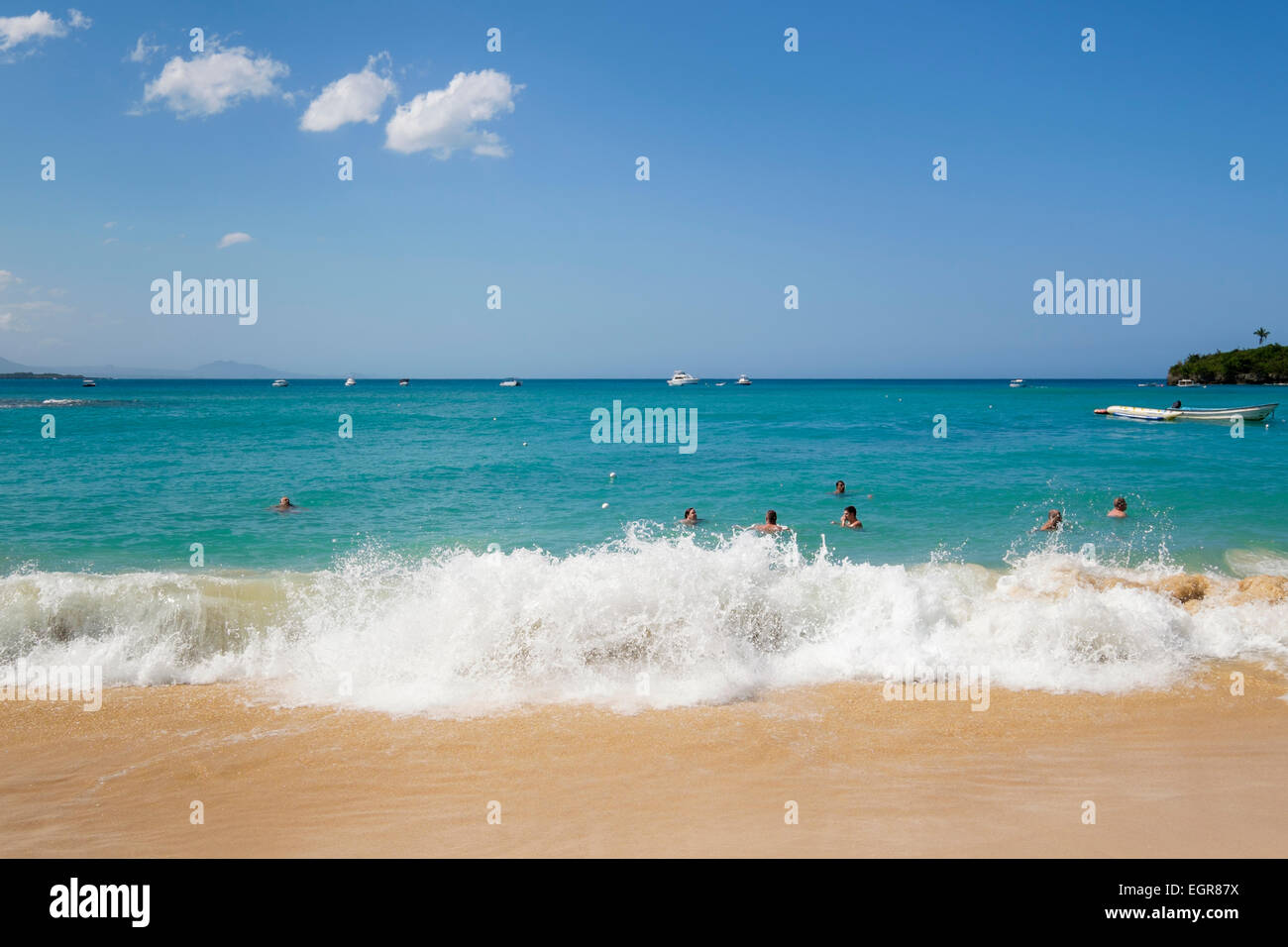 Touristes et habitants à nager dans les vagues de l'océan Atlantique dans la région de villégiature de Sosua, Puerto Plata, République dominicaine, Caraïbes Banque D'Images