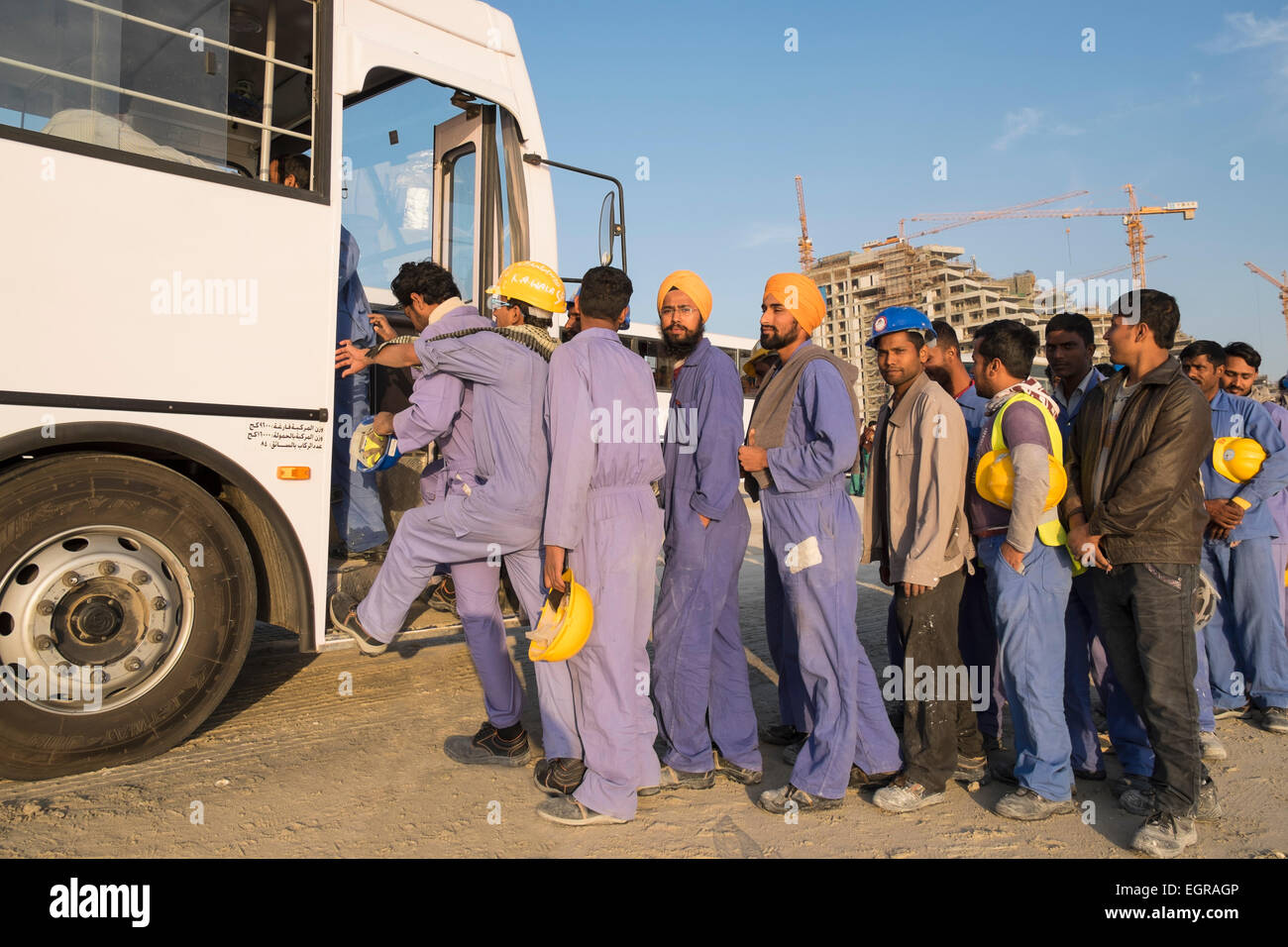 Les travailleurs de la construction d'attente afin de prendre le bus pour le logement à la fin de la journée de travail à Dubaï Émirats Arabes Unis Banque D'Images