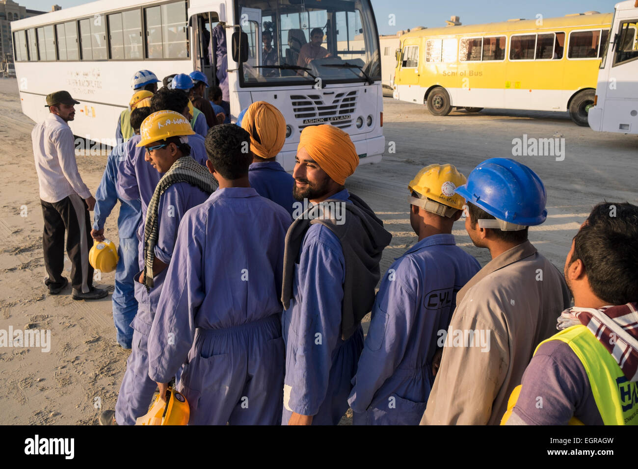 Les travailleurs de la construction d'attente afin de prendre le bus pour le logement à la fin de la journée de travail à Dubaï Émirats Arabes Unis Banque D'Images