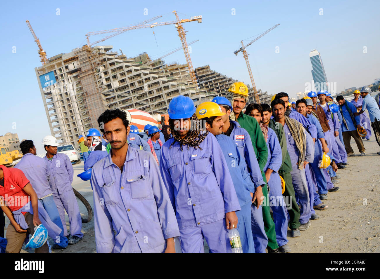 Les travailleurs de la construction d'attente afin de prendre le bus pour le logement à la fin de la journée de travail à Dubaï Émirats Arabes Unis Banque D'Images