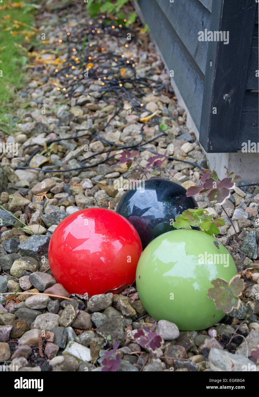 Décoration de jardin rouge vert et noir boules de décoration dans le gravier. Jardin vert en juillet, la Suède. Banque D'Images