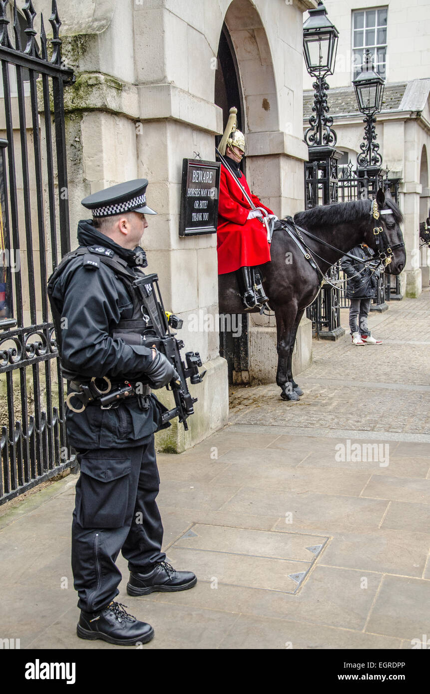 Policier armé garde la garde de cérémonie à cheval à la destination touristique populaire des Horse Guards à Whitehall, Londres, Royaume-Uni. La sécurité des armes à feu Banque D'Images