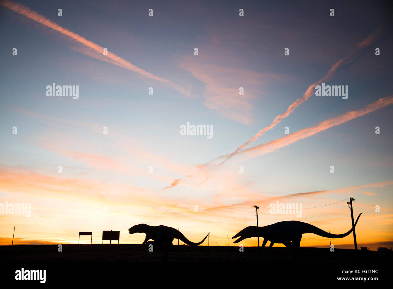 Dinosaure raptor géant chiffres découpé sur le coucher du soleil sur la route 66 près de Holbrook, Arizona USA Banque D'Images