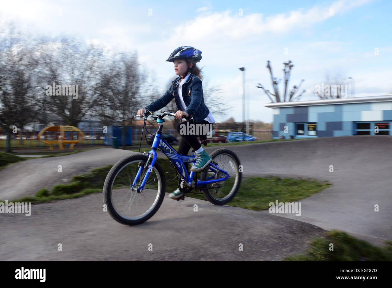 Sept ans, fille de porter un casque de vélo randonnée à vélo autour d'une piste de vélo BMX sur une froide journée d'hiver à Londres Banque D'Images