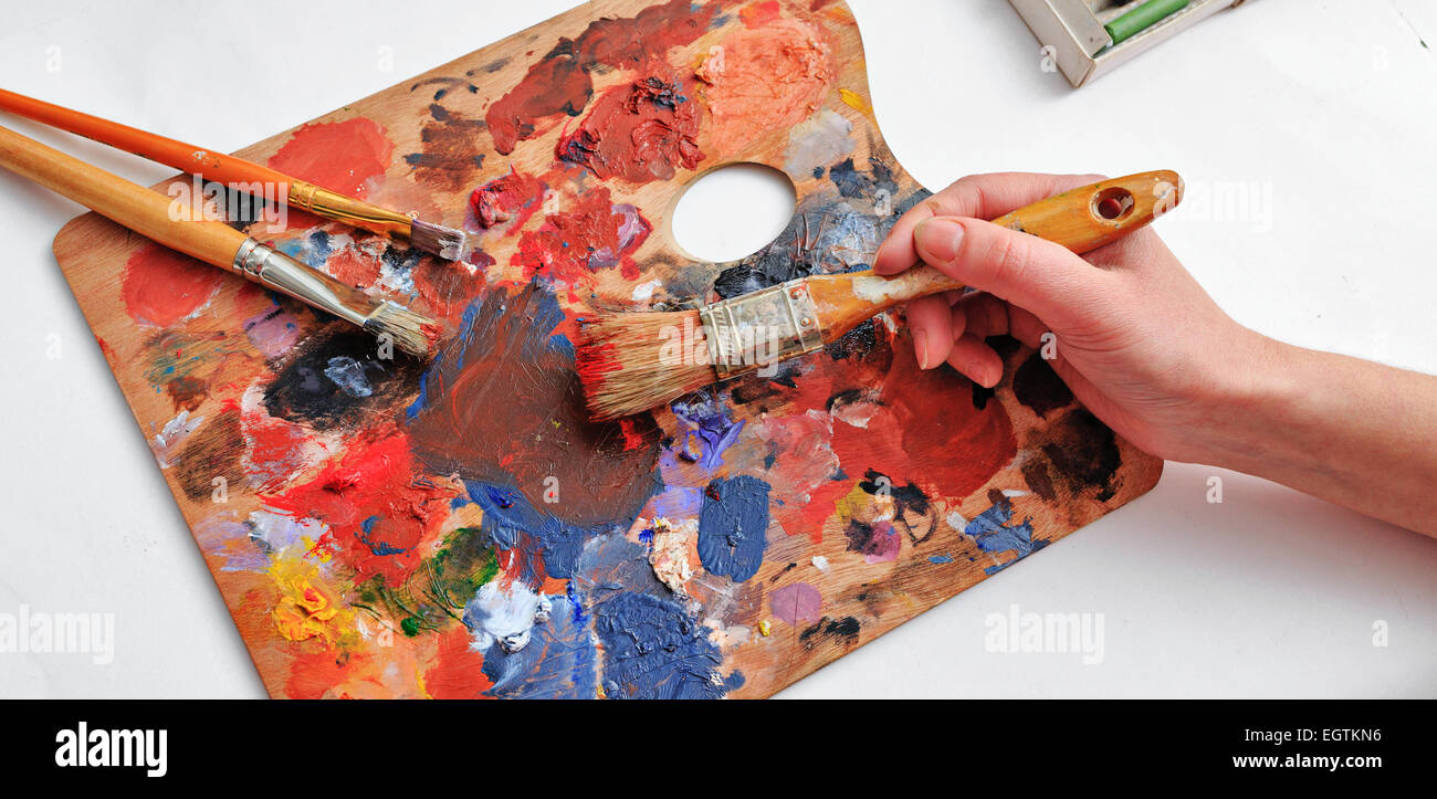 Main de l'artiste avec les pinceaux et la palette de couleurs Banque D'Images