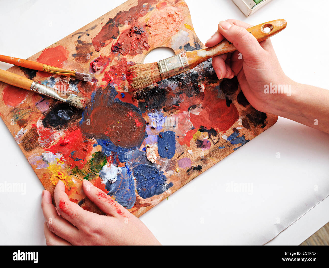 Main de l'artiste avec les pinceaux et la palette de couleurs Banque D'Images