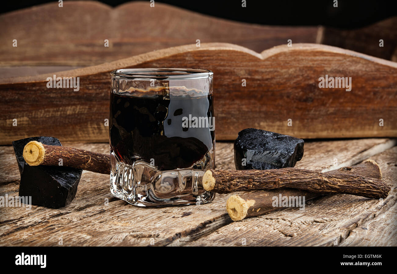 Liqueur de réglisse pure avec blocs et racines sur table en bois. Banque D'Images