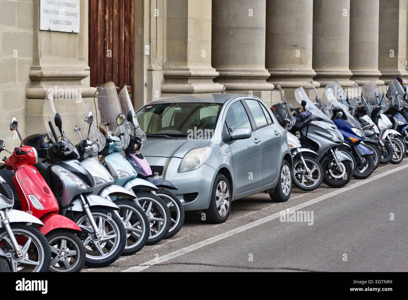 Florence, Toscane, Italie. Une petite voiture coincée dans un espace de stationnement pour motocyclettes et cyclomoteurs Banque D'Images