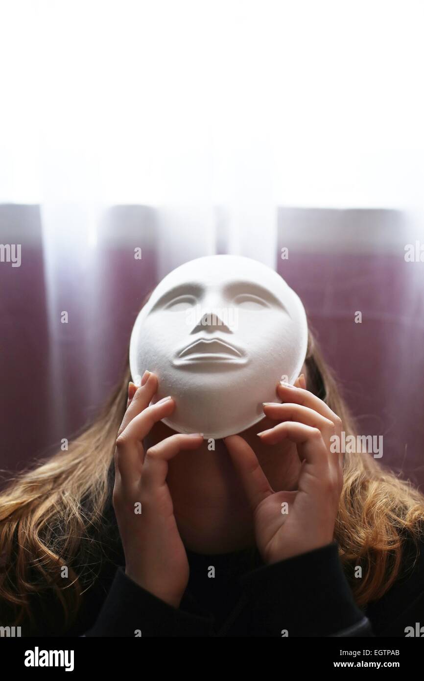 Une jeune fille portant un masque avec un visage blanc. Banque D'Images