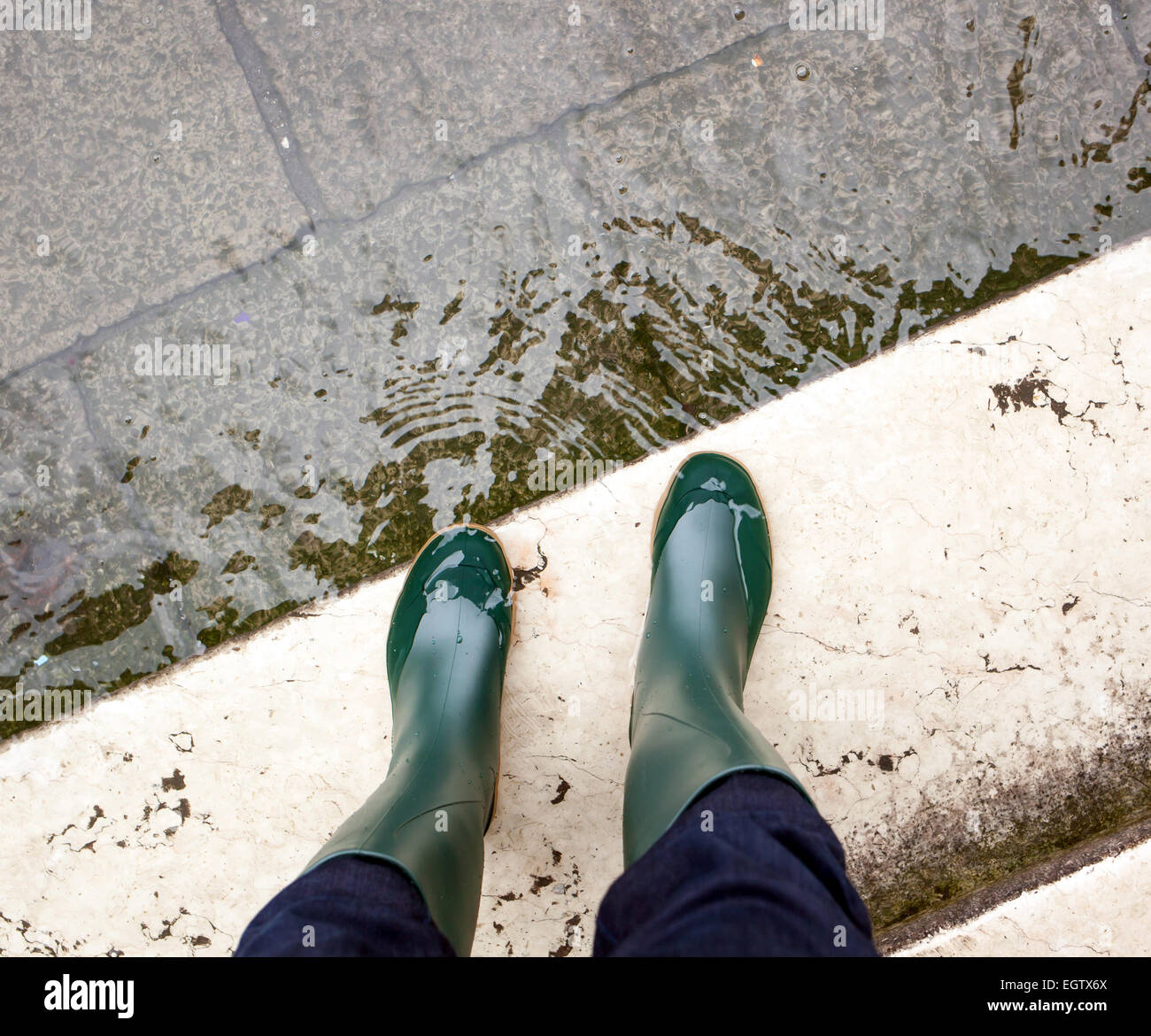 Close Up de jambes avec des bottes en raison de l'eau élevée. Cette inondation se produit lorsqu'il y a marée haute à Venise, Italie. Banque D'Images