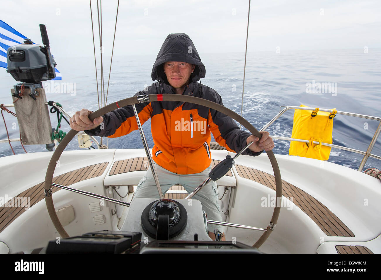 Jeune homme skipper dans la mer à la barre d'un yacht à voile Photo Stock -  Alamy