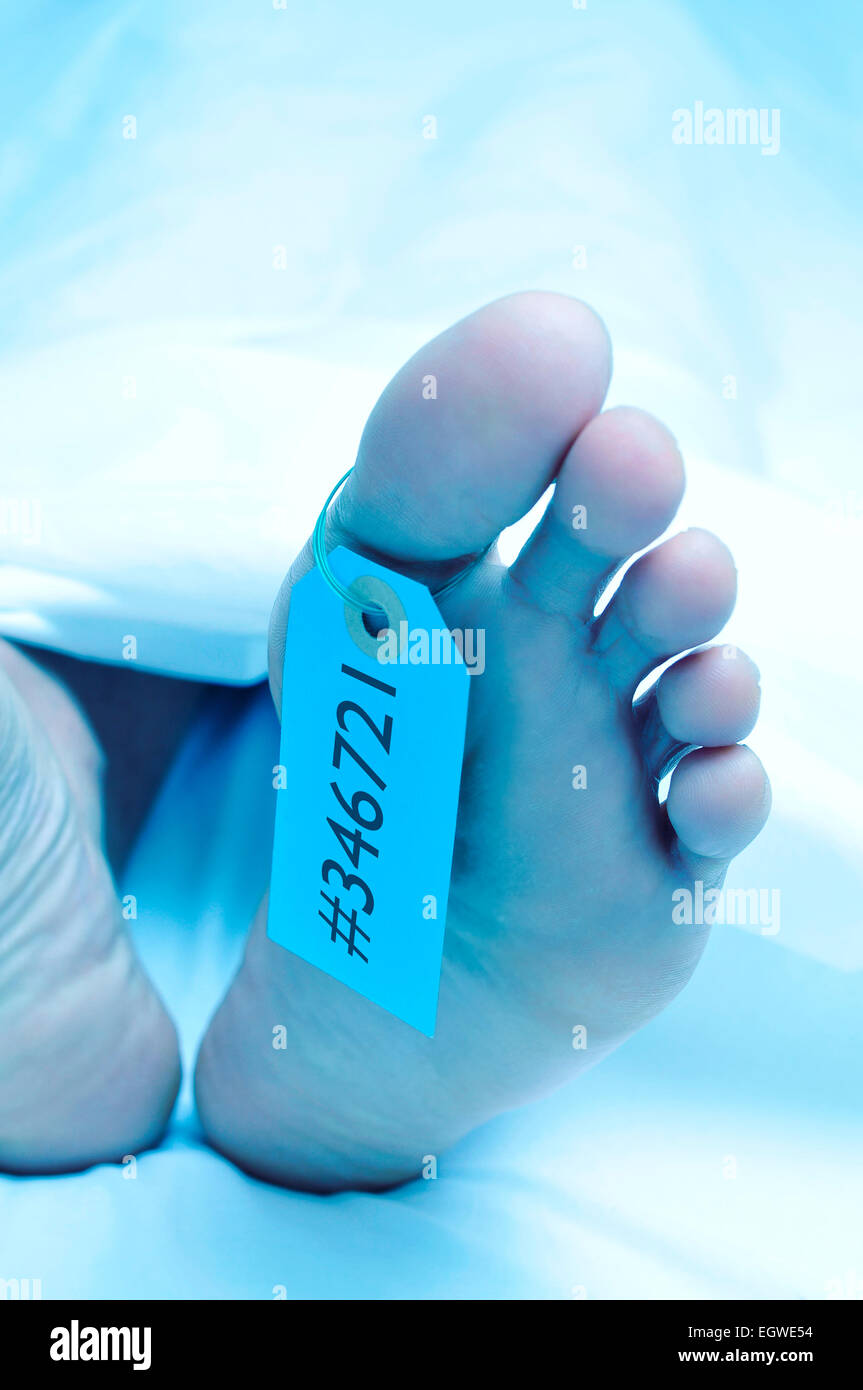 Gros plan des pieds d'un corps mort recouvert d'une feuille et à une étiquette avec un numéro d'identification attaché sur le gros orteil Banque D'Images
