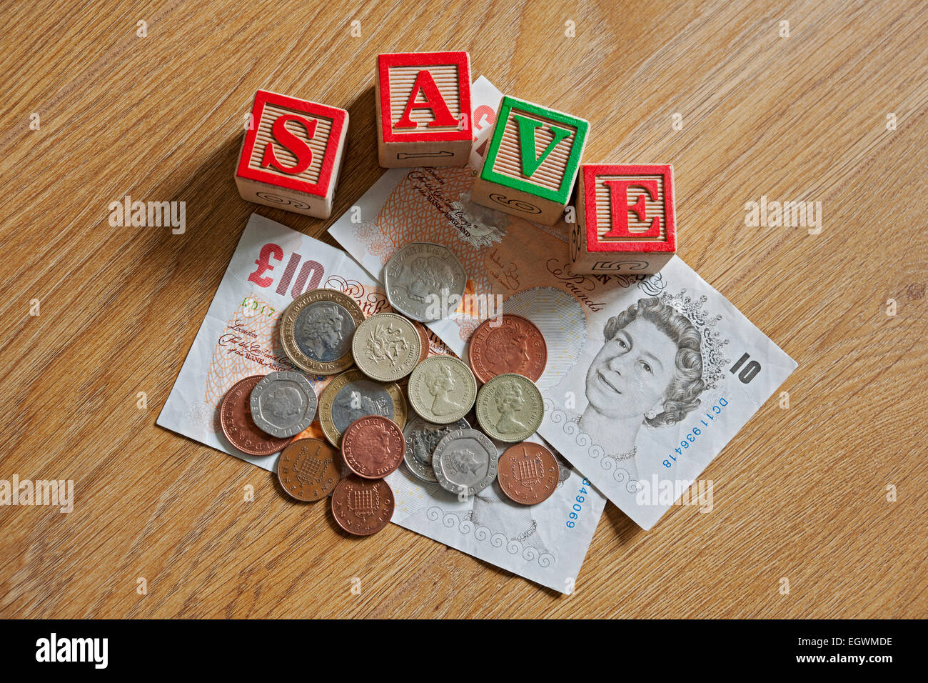 Briques en bois blocs de construction jouet orthographiant le mot sauver et l'argent anglais Cash coins finance concept d'affaires close up Banque D'Images