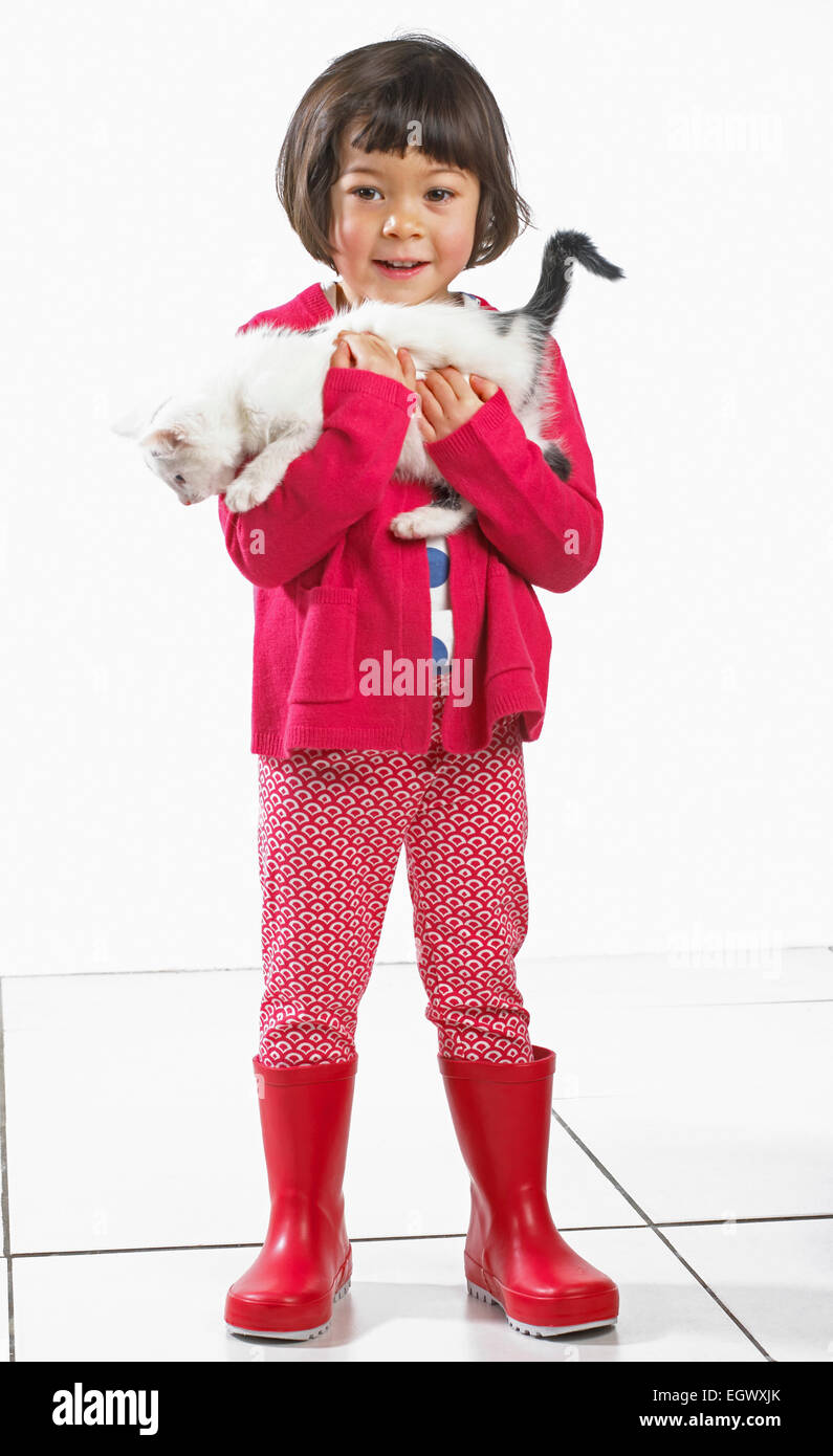 Jeune fille debout tenant un chaton, 2 ans Banque D'Images