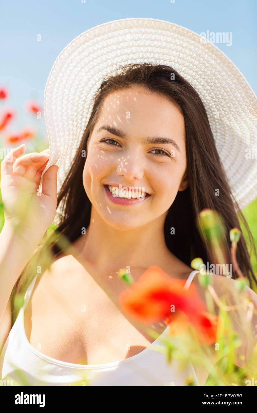 Smiling young woman in straw hat sur champ de coquelicots Banque D'Images