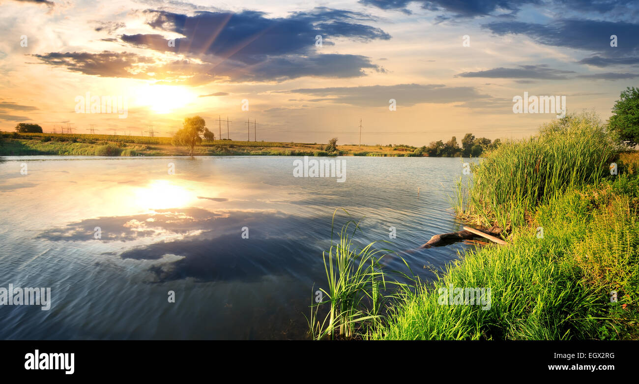Reflet de nuages dans une rivière calme au coucher du soleil Banque D'Images