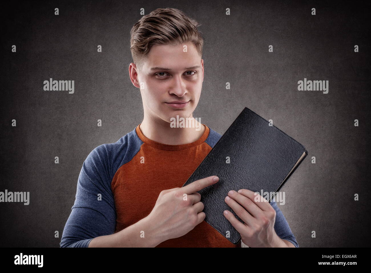 Jeune homme pointant un gros livre avec des couvertures en cuir Banque D'Images