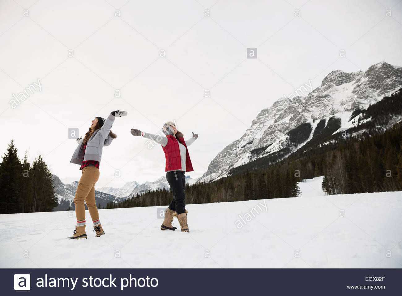 Les femmes avec les bras tendus en champ neigeux Banque D'Images