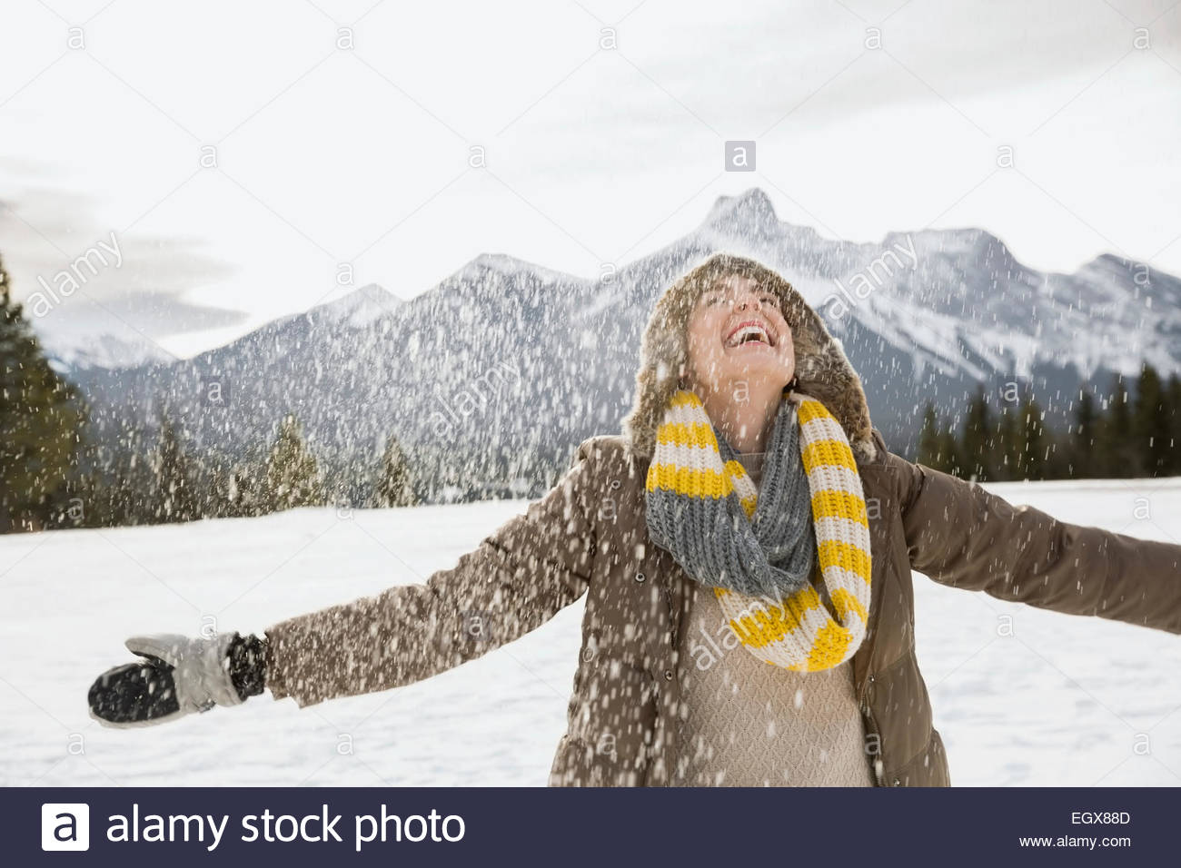 La neige qui tombe autour d'exubérante woman with arms outstretched Banque D'Images