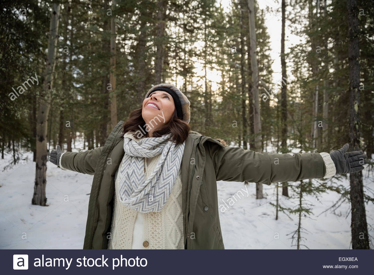 Femme exubérante with arms outstretched in Snowy Woods Banque D'Images