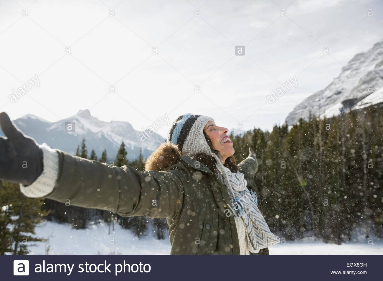 Femme exubérante avec bras tendus au-dessous de la montagne enneigée Banque D'Images