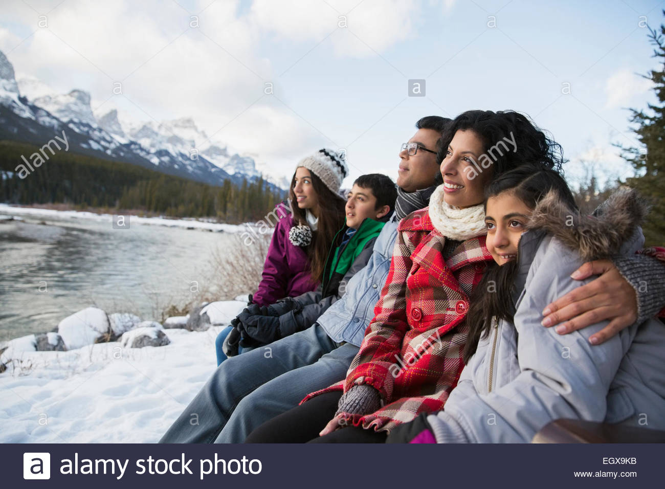 Famille à la recherche de là sur un banc de neige à Riverside Banque D'Images