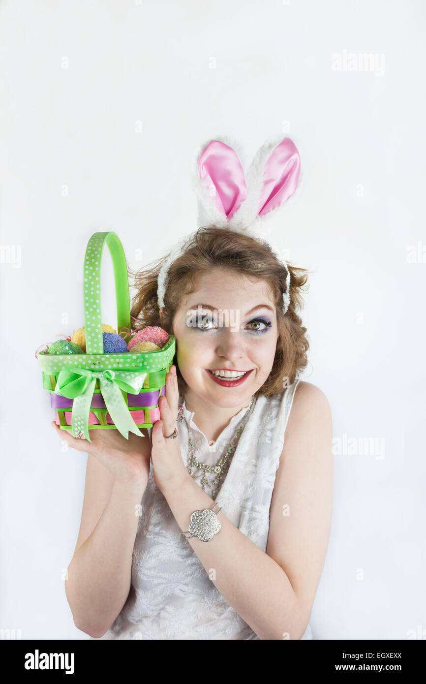 Belle jeune femme portant des oreilles de lapin et holding Easter basket avec des oeufs de Pâques. Banque D'Images