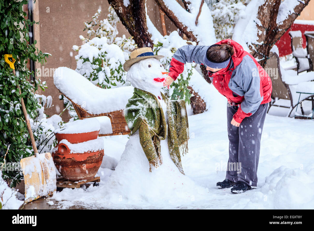 La femme est de faire un bonhomme de neige dans sa cour pendant une tempête de neige Banque D'Images