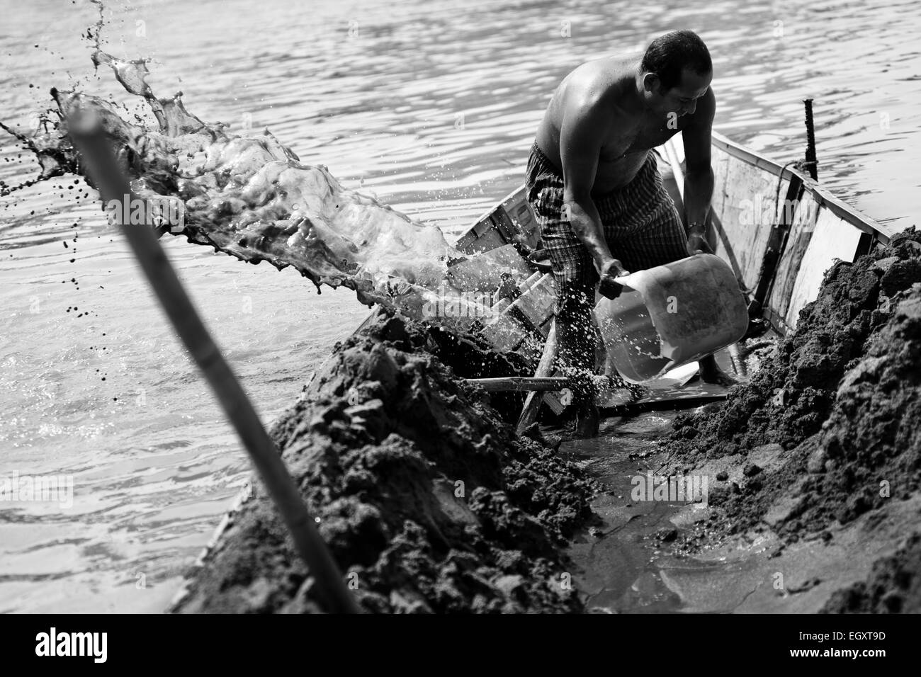 Un mineur à étriers de sable l'eau hors du bateau ancré au milieu de la rivière La Vieja à Cartago, Colombie. Banque D'Images