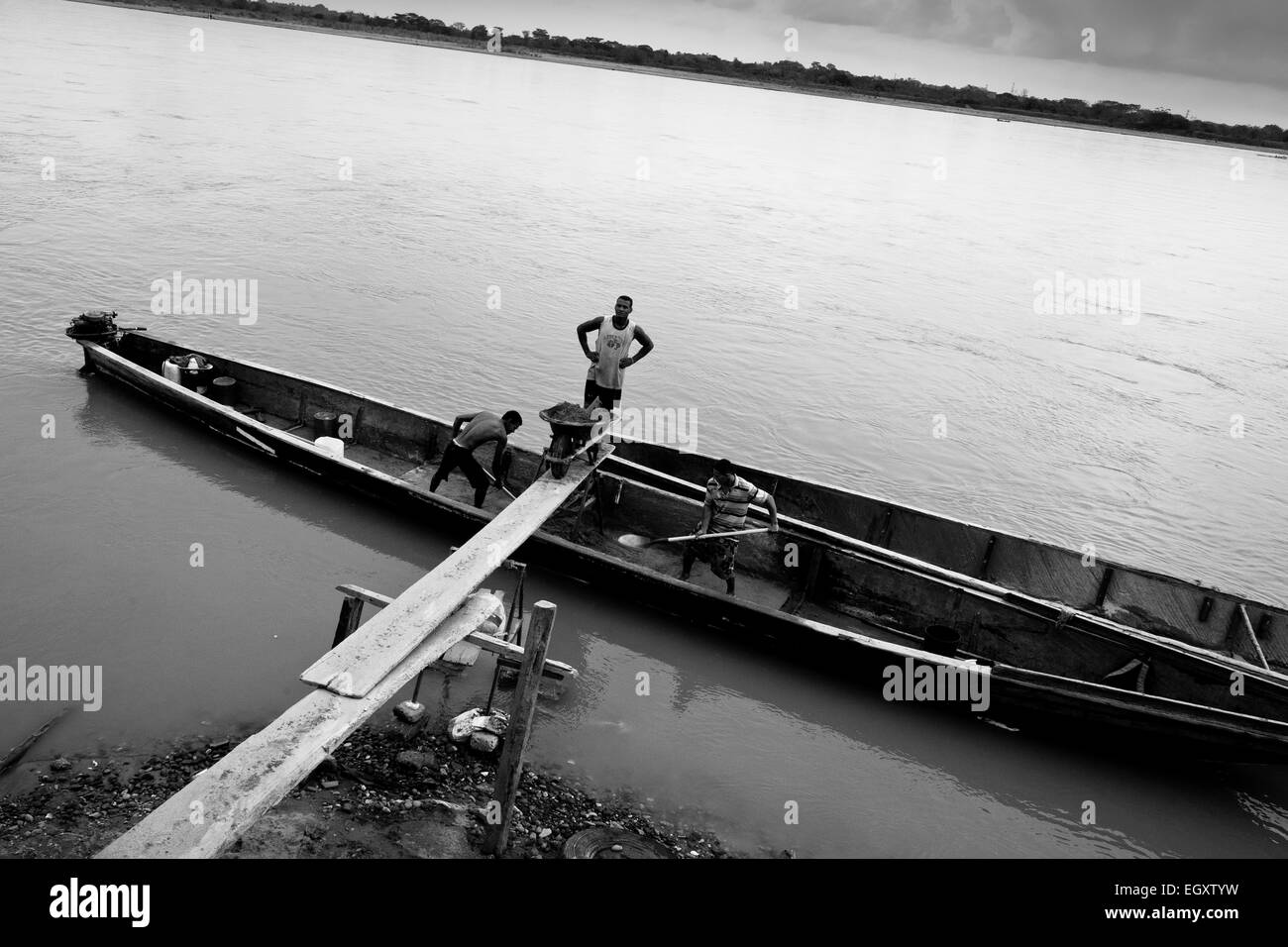 Les mineurs, à l'aide de sable colombien une brouette, décharger le sable du bateau sur la rive de la rivière à Puerto Berrío, Colombie. Banque D'Images