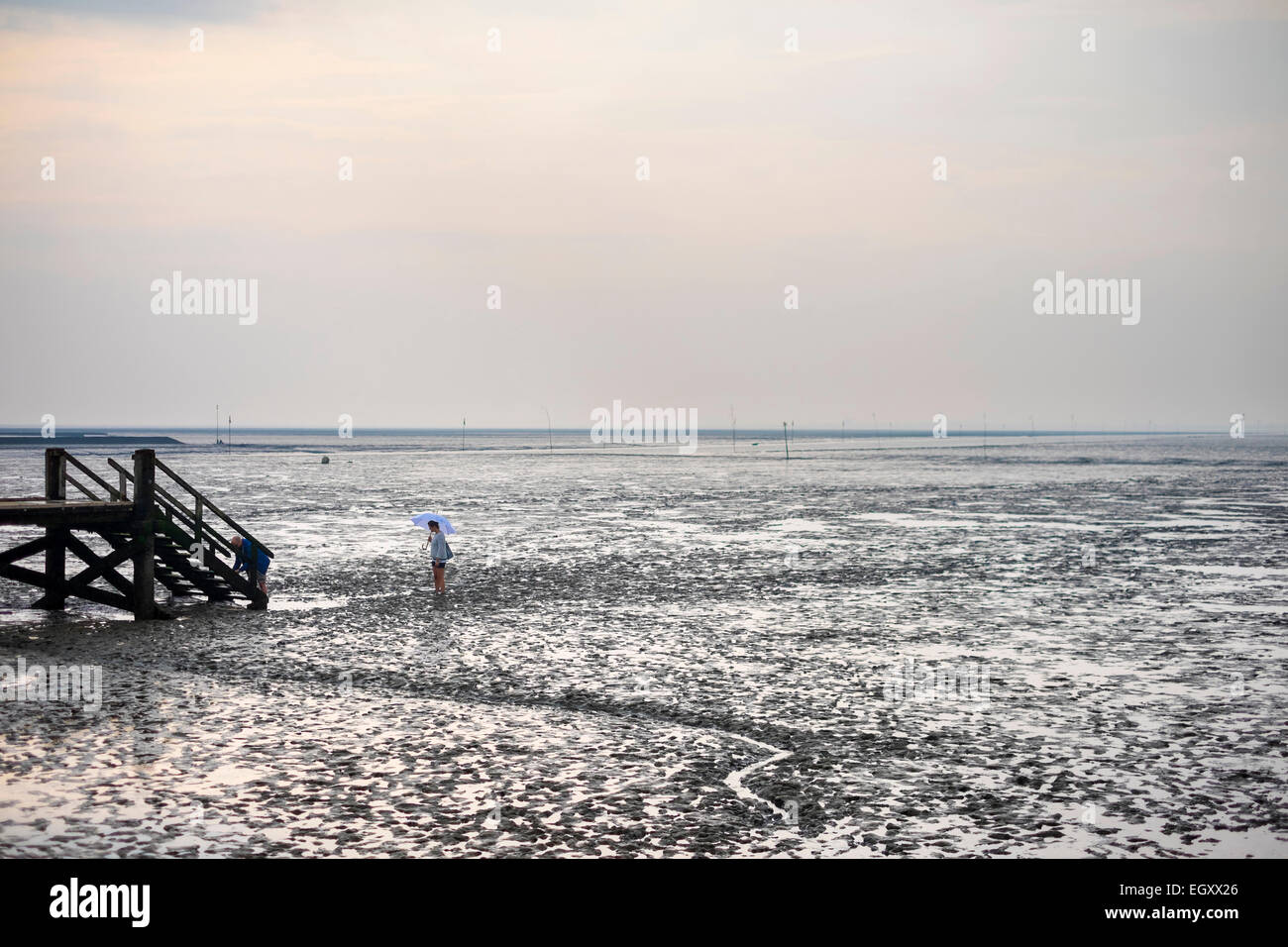 Jeune femme marche dans les vasières de la mer des Wadden (Wattenmeer) à marée basse Banque D'Images