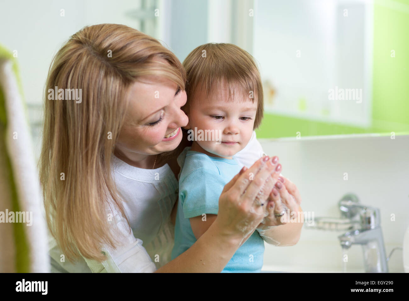 Kid boy se laver les mains avec du savon dans la salle de bains Banque D'Images
