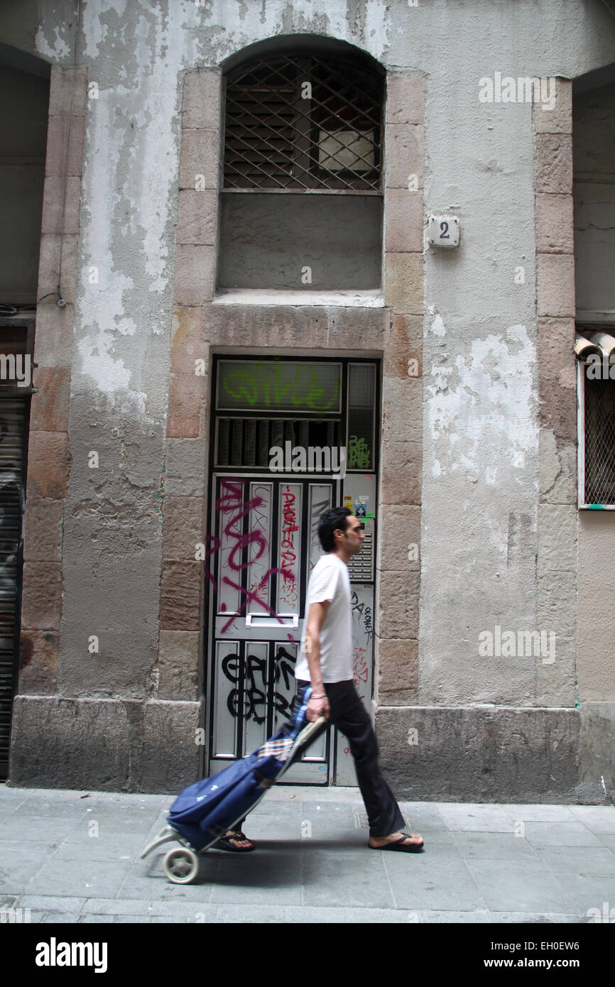 Homme avec panier en passant devant la rue de la vieille porte dans le quartier El Raval, dans le centre de Barcelone Banque D'Images