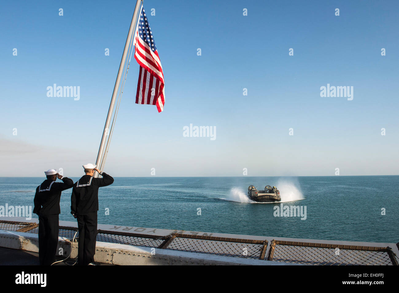 Golfe Arabique (fév. 25, 2015) Seaman Derrius Ross, à gauche, à Portsmouth, en Virginie, et les communications de masse 3e classe Andrew Sneeringer Spécialiste, de Sacramento, Californie, saluer le drapeau national au cours de matin à bord de la couleurs dock de transport amphibie USS New York (LPD 21) comme Landing Craft Air Cushion (LCAC) 27, affecté à l'unité d'Assaut (ACU) 4, s'apprête à entrer dans le pont du coffre. New York fait partie de l'Iwo Jima Groupe amphibie et, avec l'entrepris 24e Marine Expeditionary Unit (MEU) 24, est déployé à l'appui d'opérations de sécurité maritime et sécurité théâtre coopérati Banque D'Images