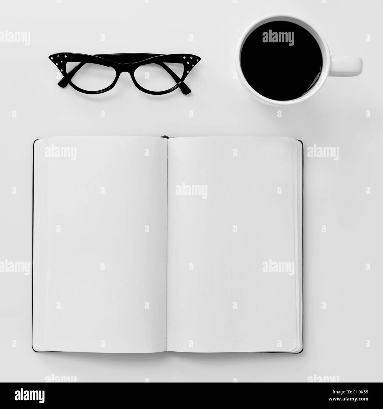 Capture d'un grand angle d'un ordinateur portable, une paire de lunettes cerclées de noir en plastique pour les femmes et une tasse de café sur un tableau blanc Banque D'Images