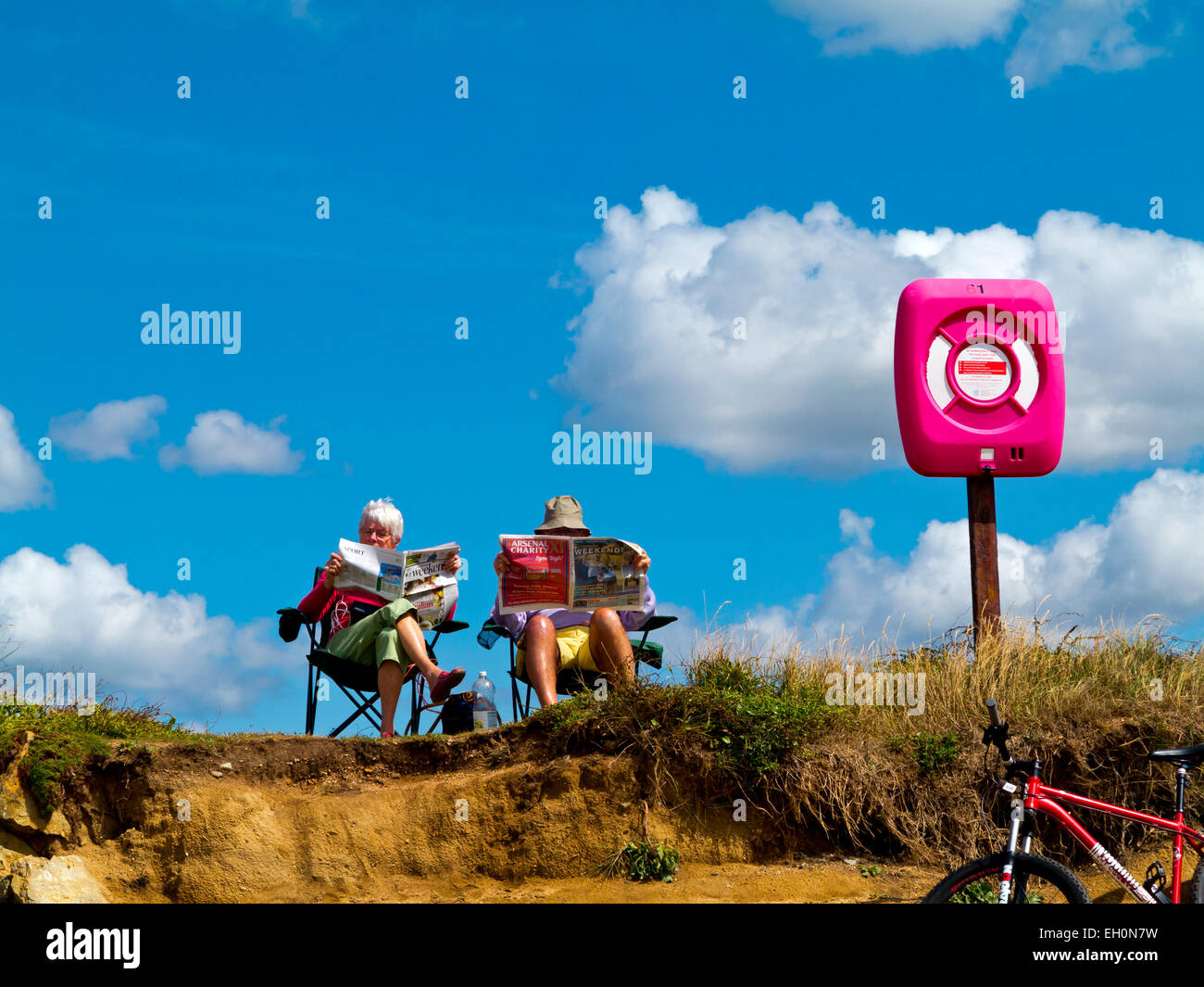 Couple de personnes âgées assis sur des transats sur la plage de lecture Burton Bradstock dans Dorset sur la côte sud-ouest de l'Angleterre, Royaume-Uni Banque D'Images