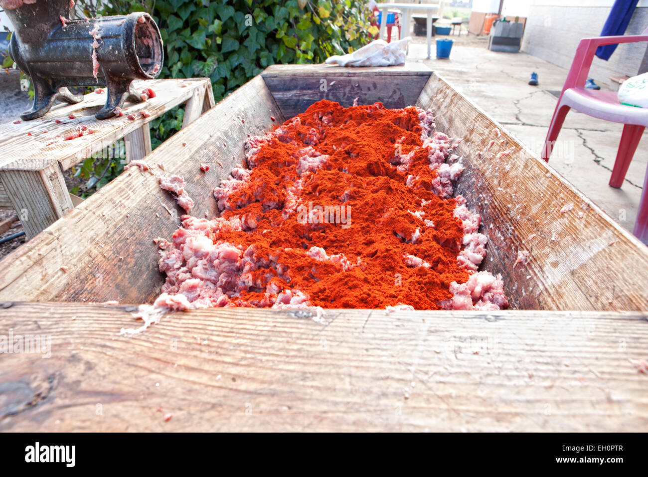 L'auge en bois pleine de viande crue au sol recouvert d'épices juste avant d'être mélangés pour getchorizo ou saucisses. Accueil traditionnel sl Banque D'Images