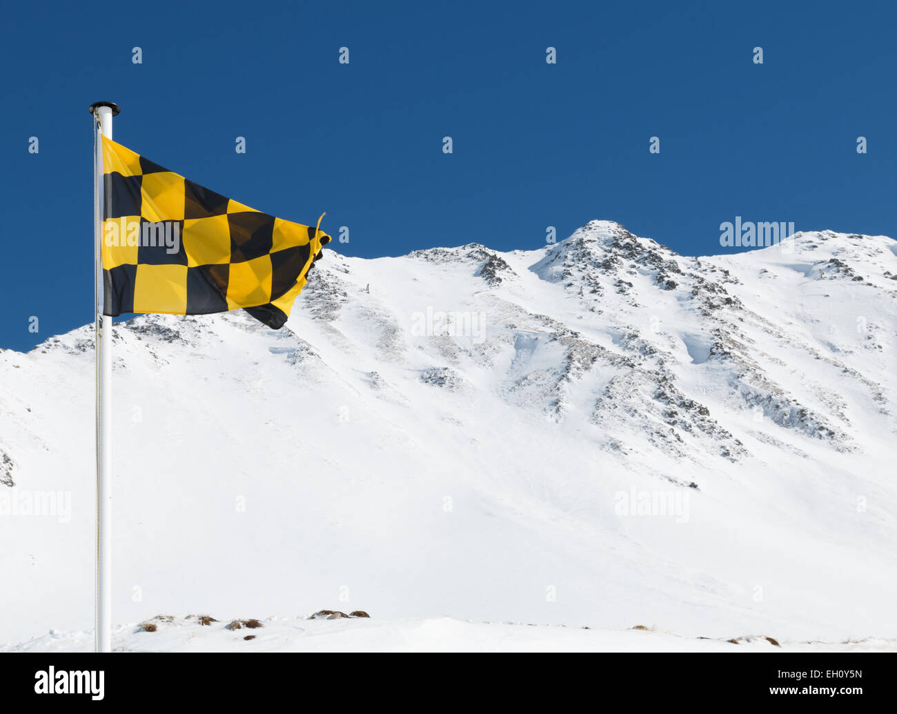 Jaune et Noir du drapeau d'avertissement de danger d'avalanche avec une crête de montagne derrière. Risque élevé d'avalanche Banque D'Images