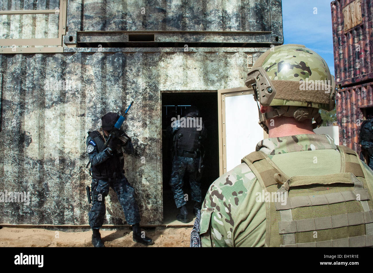 Un soldat de l'armée américaine béret vert des forces spéciales conseille tigres hondurien des soldats alors qu'ils effacer un composé au cours de l'entraînement le 27 février 2015 sur la base aérienne d'Eglin, en Floride. Banque D'Images